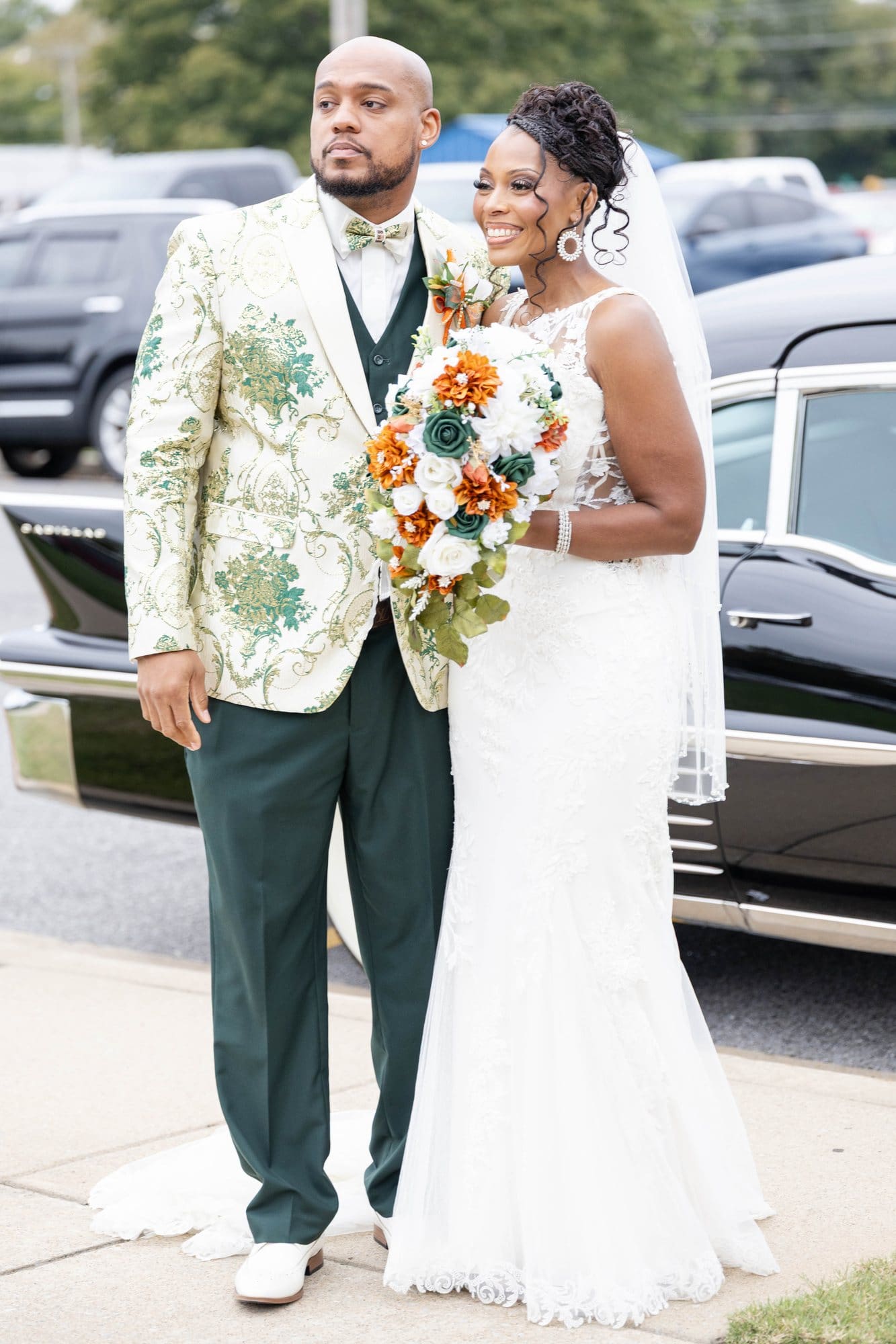 David and Nikeesha smiling outside the church beside their vintage Cadillac