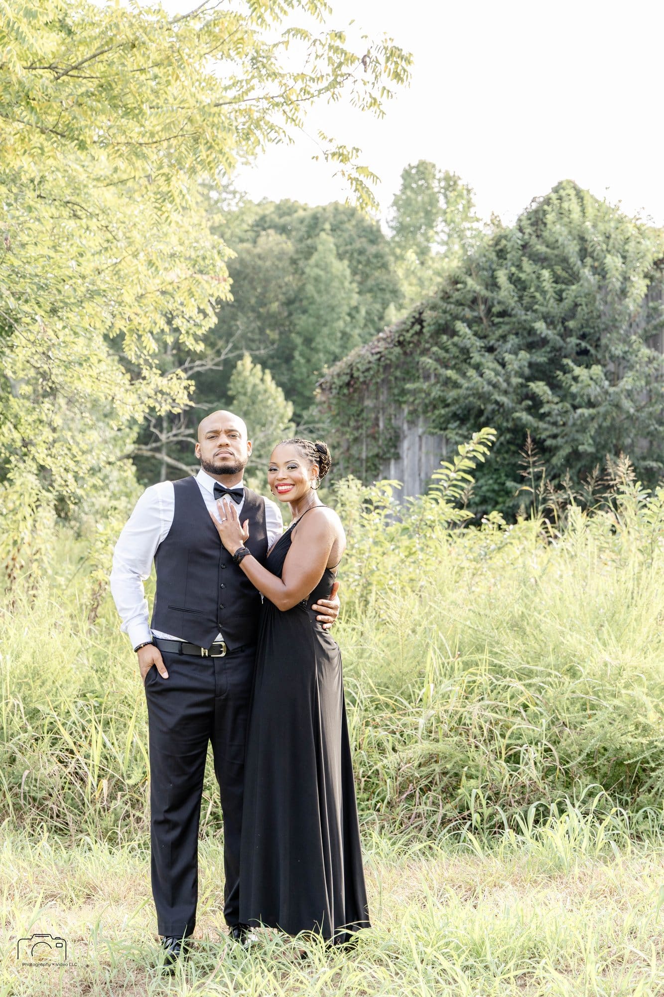 David and Nikeesha standing together in tall grass beside an old ivy-covered barn at Land Between the Lakes, Kentucky