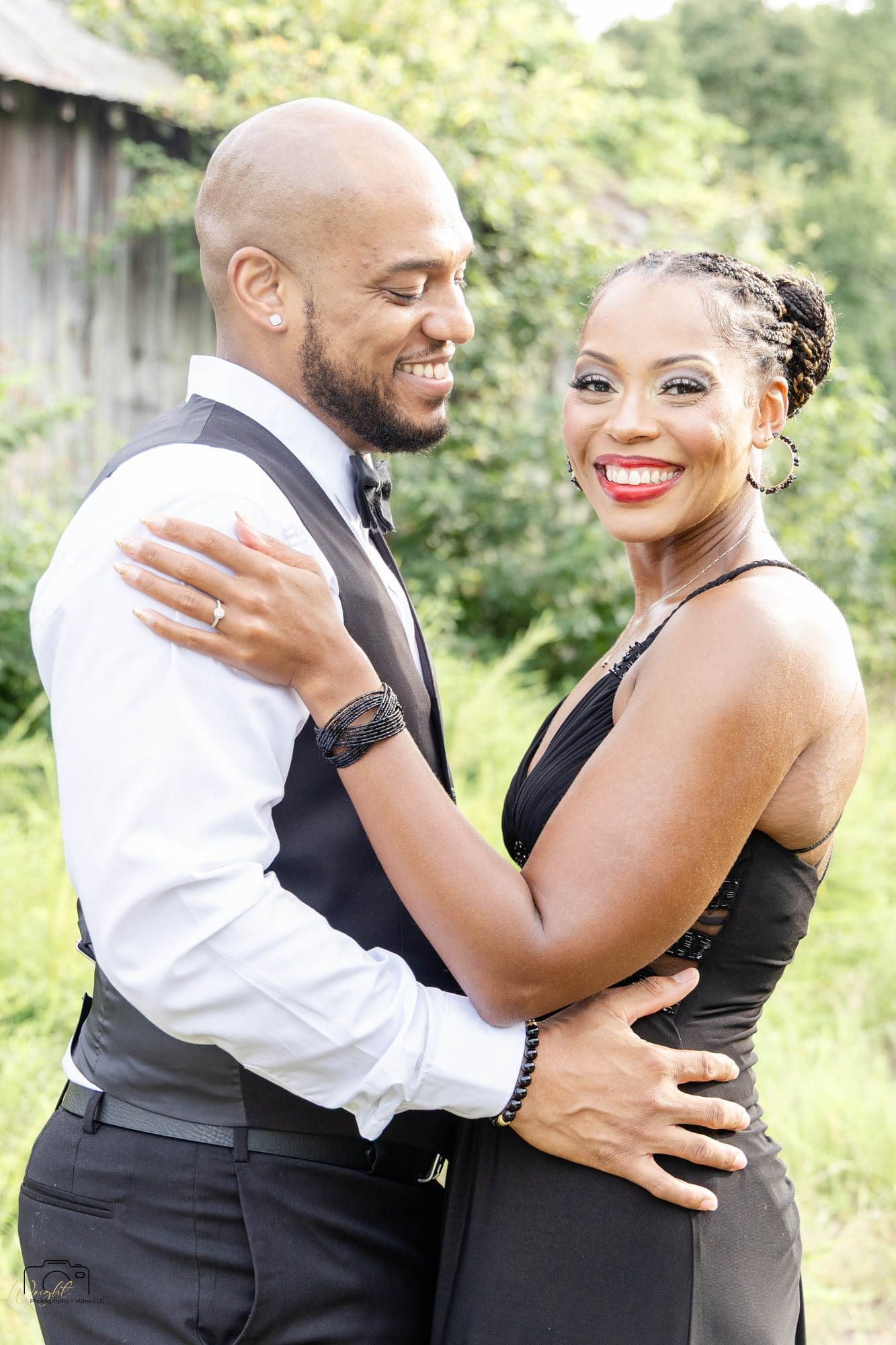 David and Nikeesha embracing and smiling in formal black attire in a grassy field at Land Between the Lakes, Kentucky
