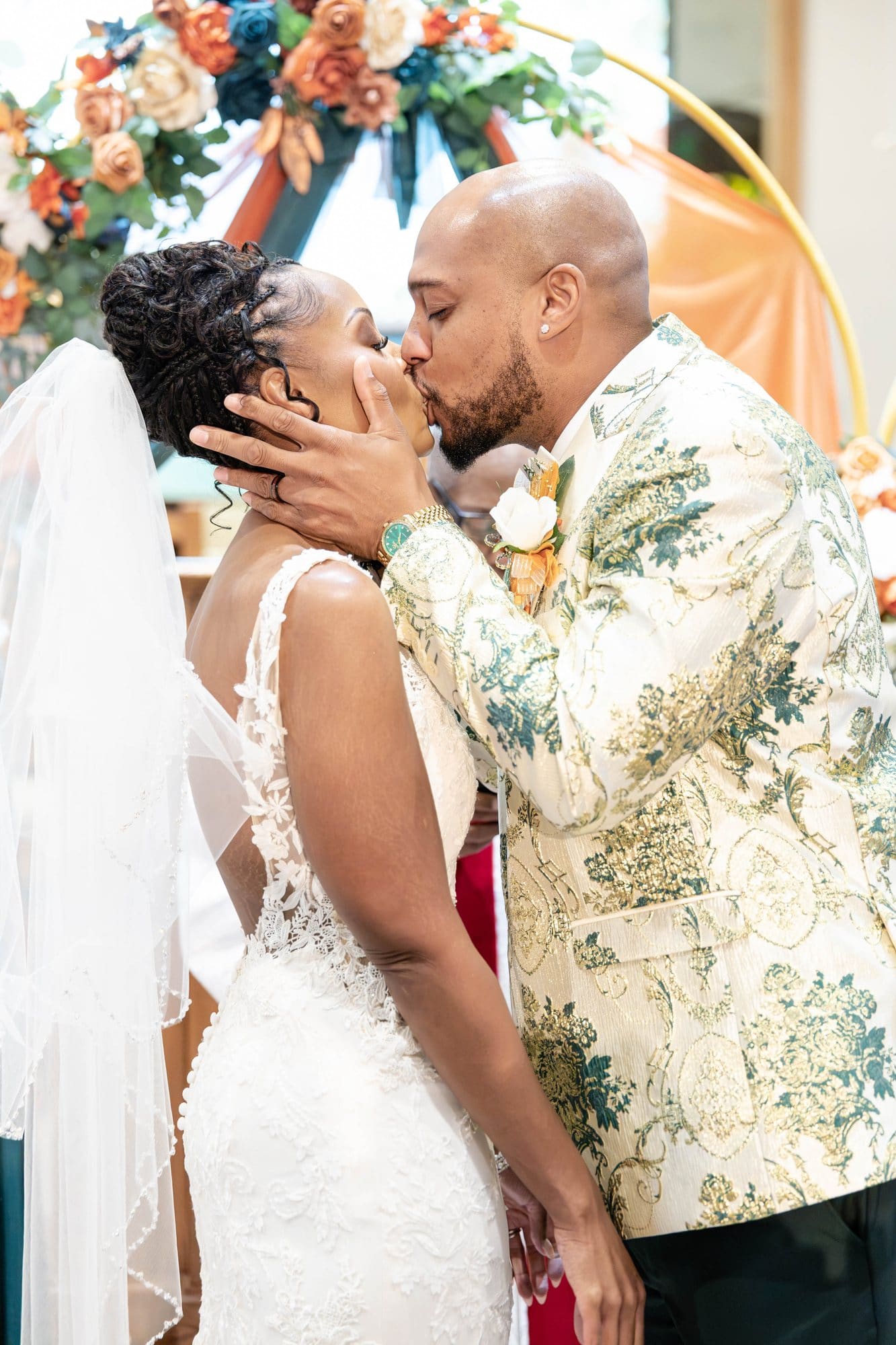 David and Nikeesha sharing their first kiss as husband and wife beneath the floral arch