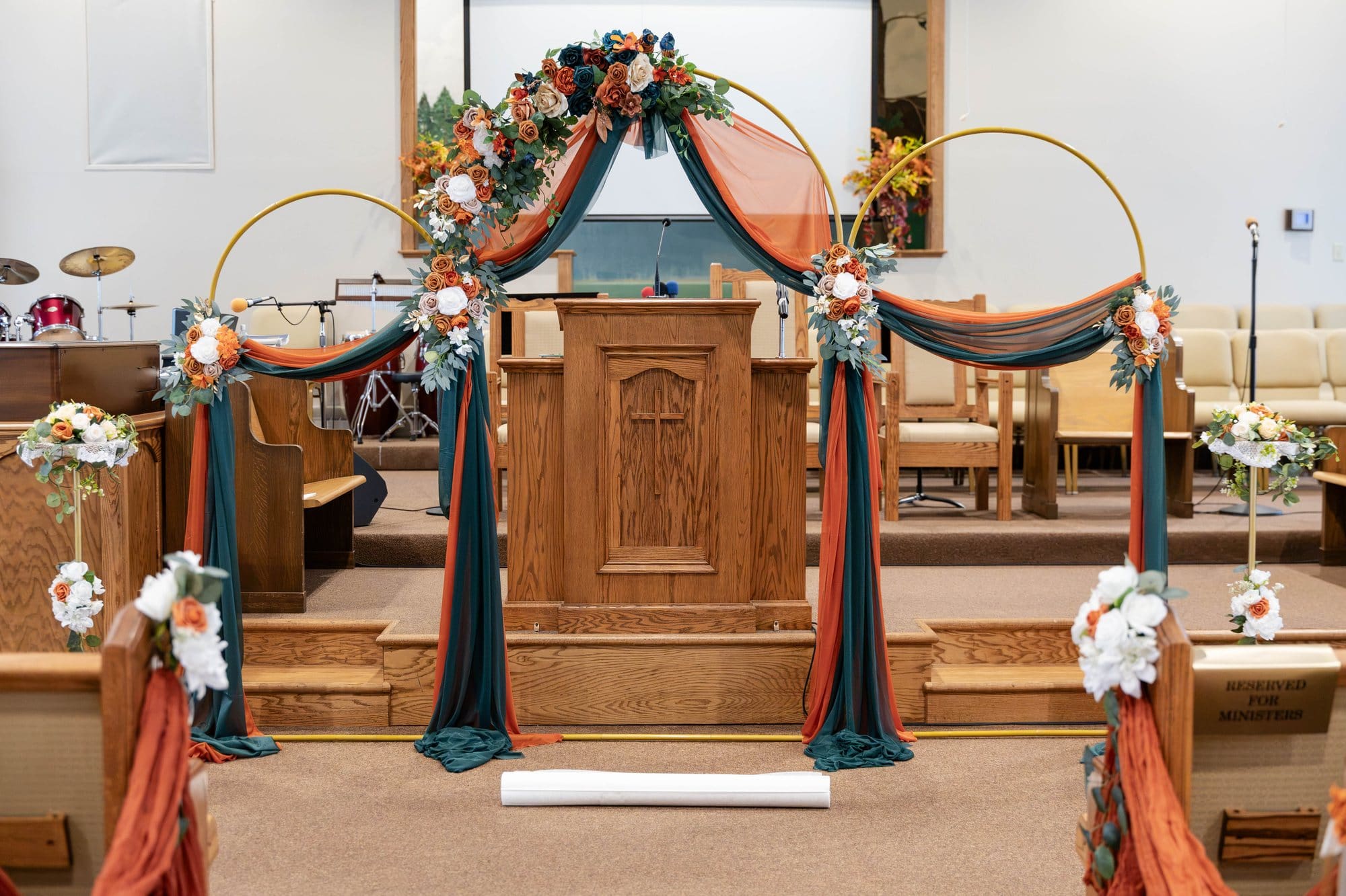 Gold hoop ceremony arch draped in emerald and spiced copper with roses at Mount Moriah Missionary Baptist Church in Paducah, KY