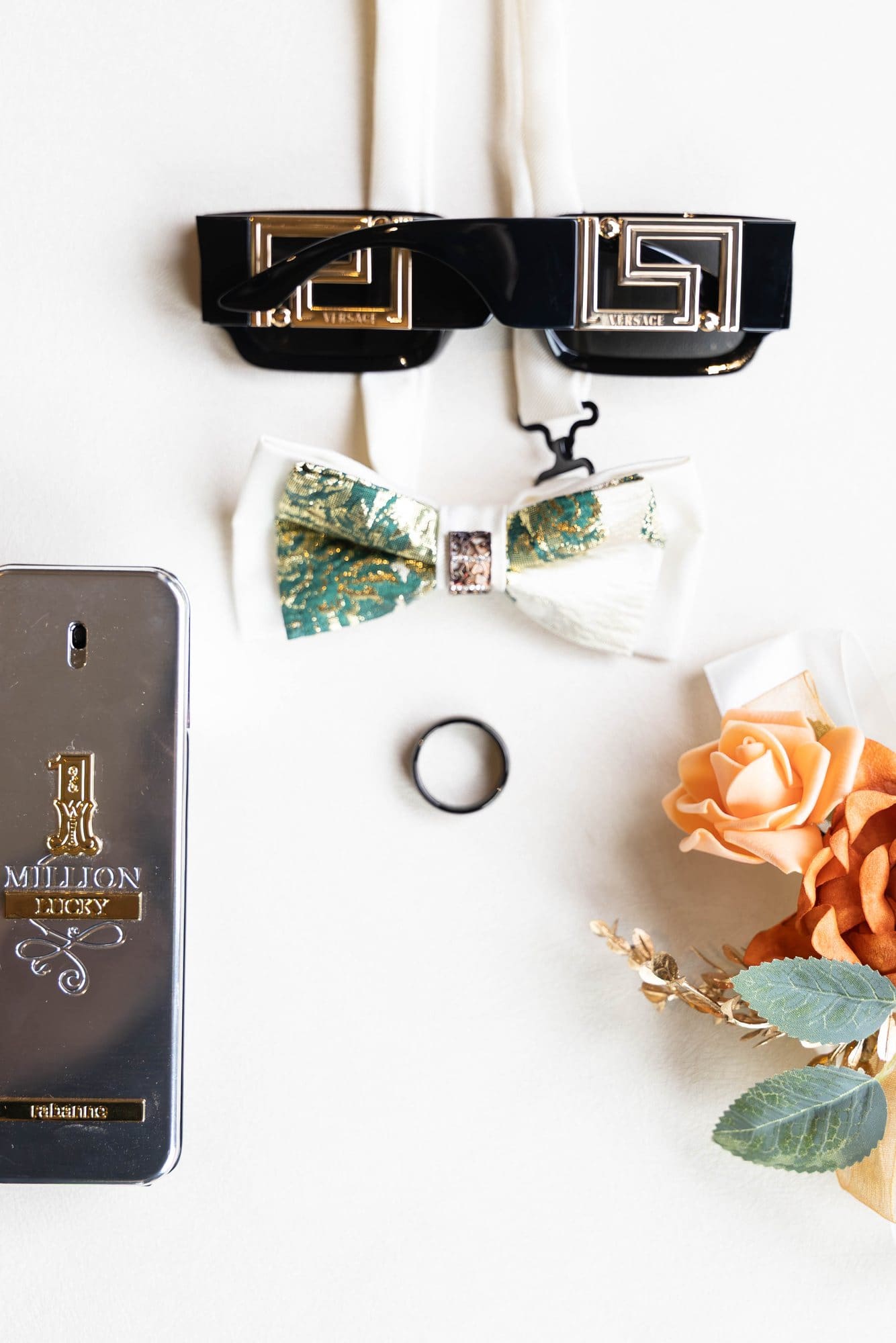 Groom's details: brocade bow tie, black ring and sunglasses styled with orange roses