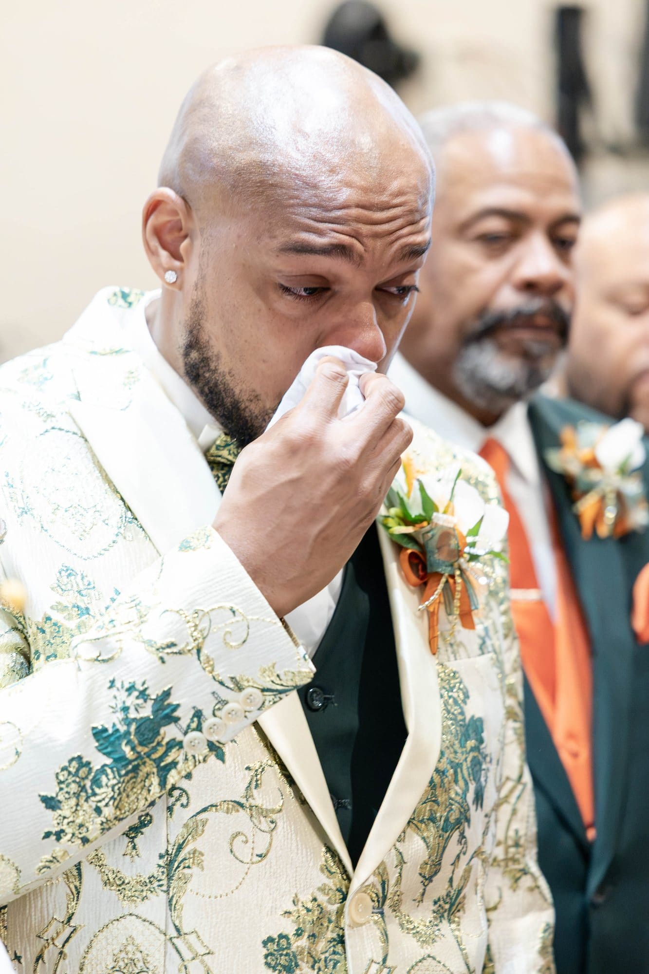 David wiping a tear from his eye as his father stands beside him at the altar