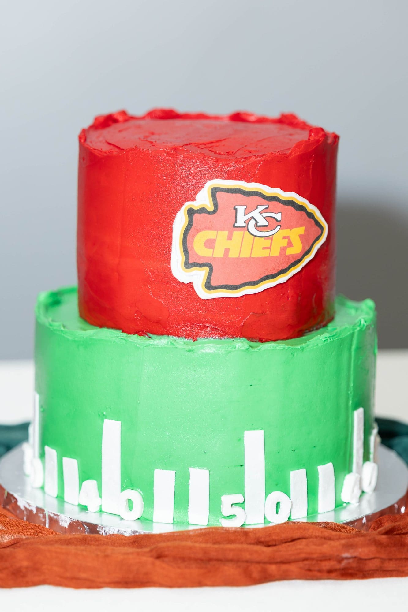 Red and green football field groom's cake topped with a Chiefs arrowhead