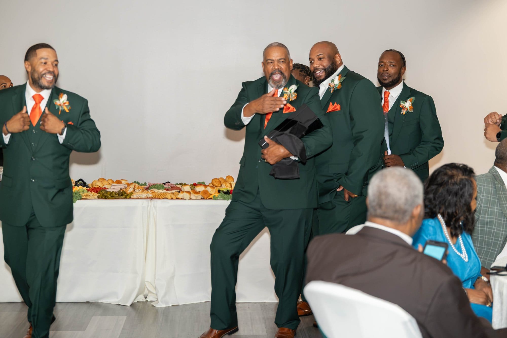 Groomsmen in emerald suits with copper ties dancing into the reception