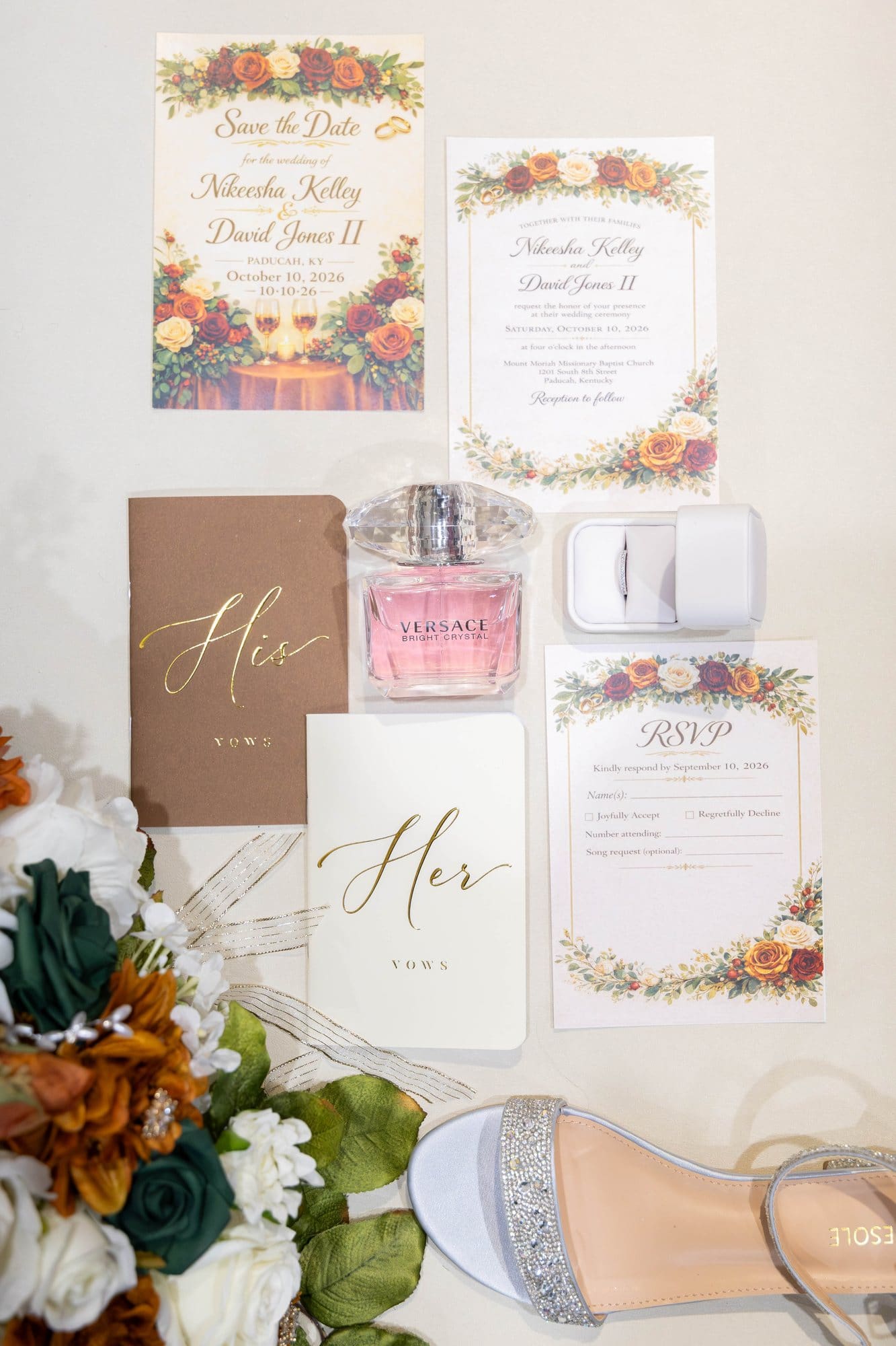 Wedding invitation suite with gold foil vow books, perfume and crystal sandals styled with copper and emerald florals