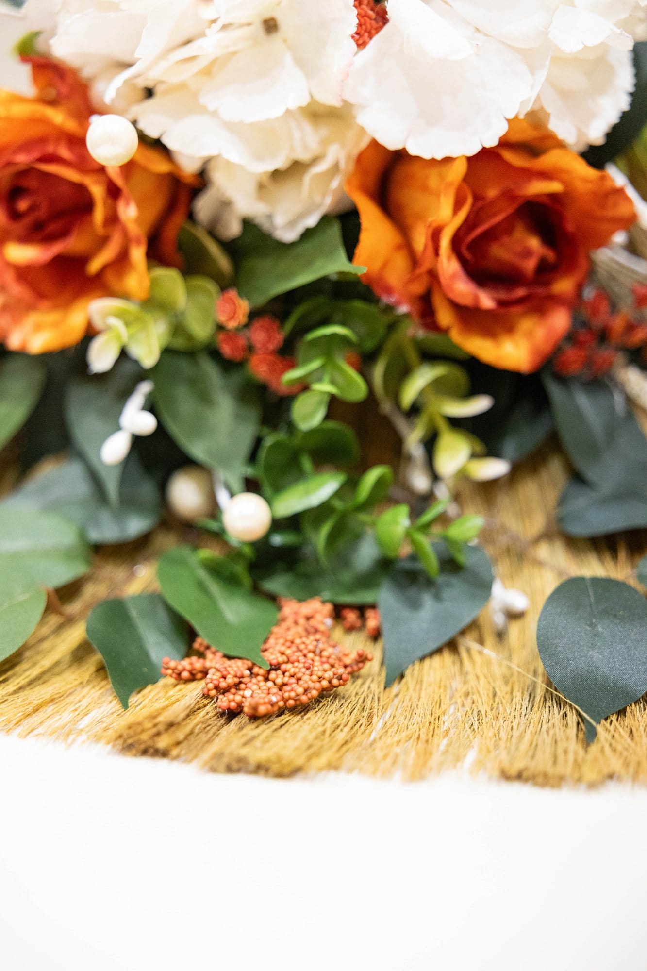 Wedding broom dressed in orange and white roses and greenery, ready for the jumping the broom tradition