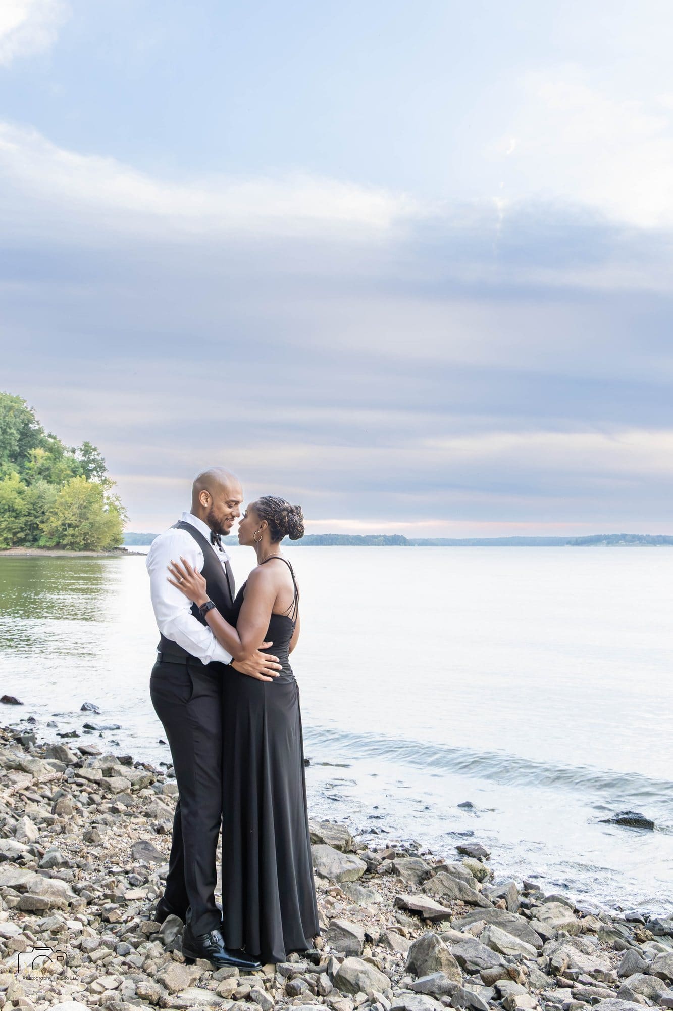 David and Nikeesha embracing at the water's edge on Kentucky Lake beneath a soft pink and gray sky