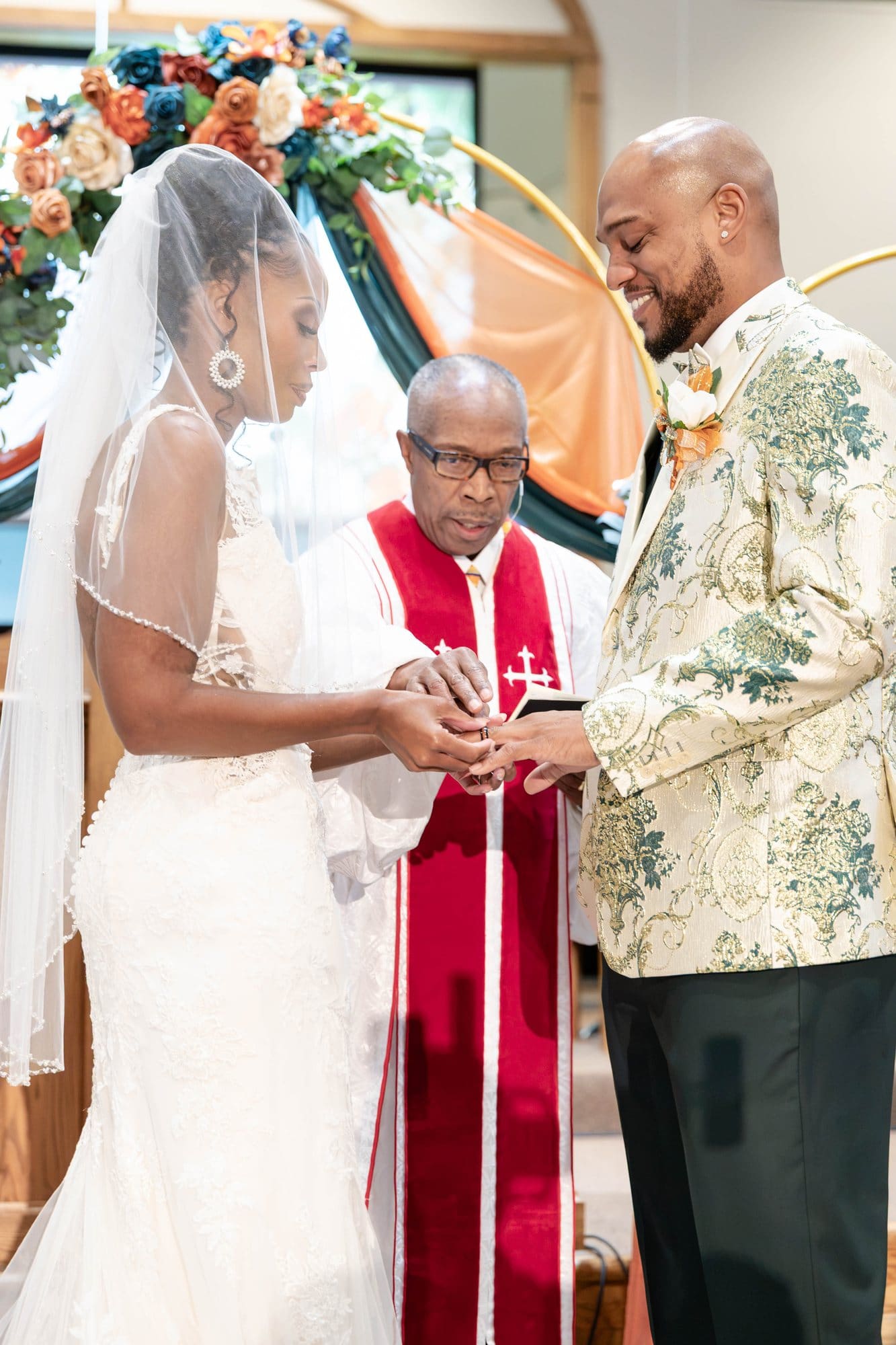 David and Nikeesha exchanging rings at the altar while the officiant looks on