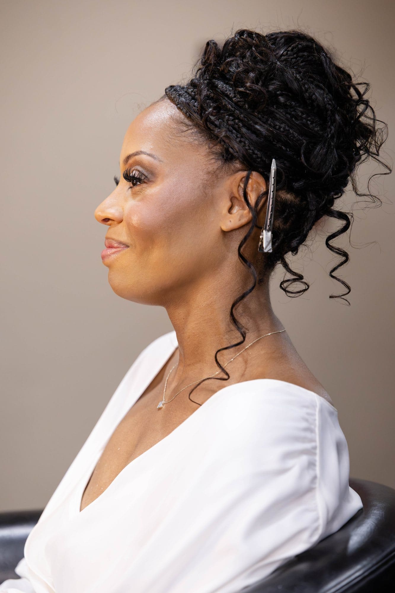 Nikeesha in profile in the salon chair with her hair styled in an elegant updo