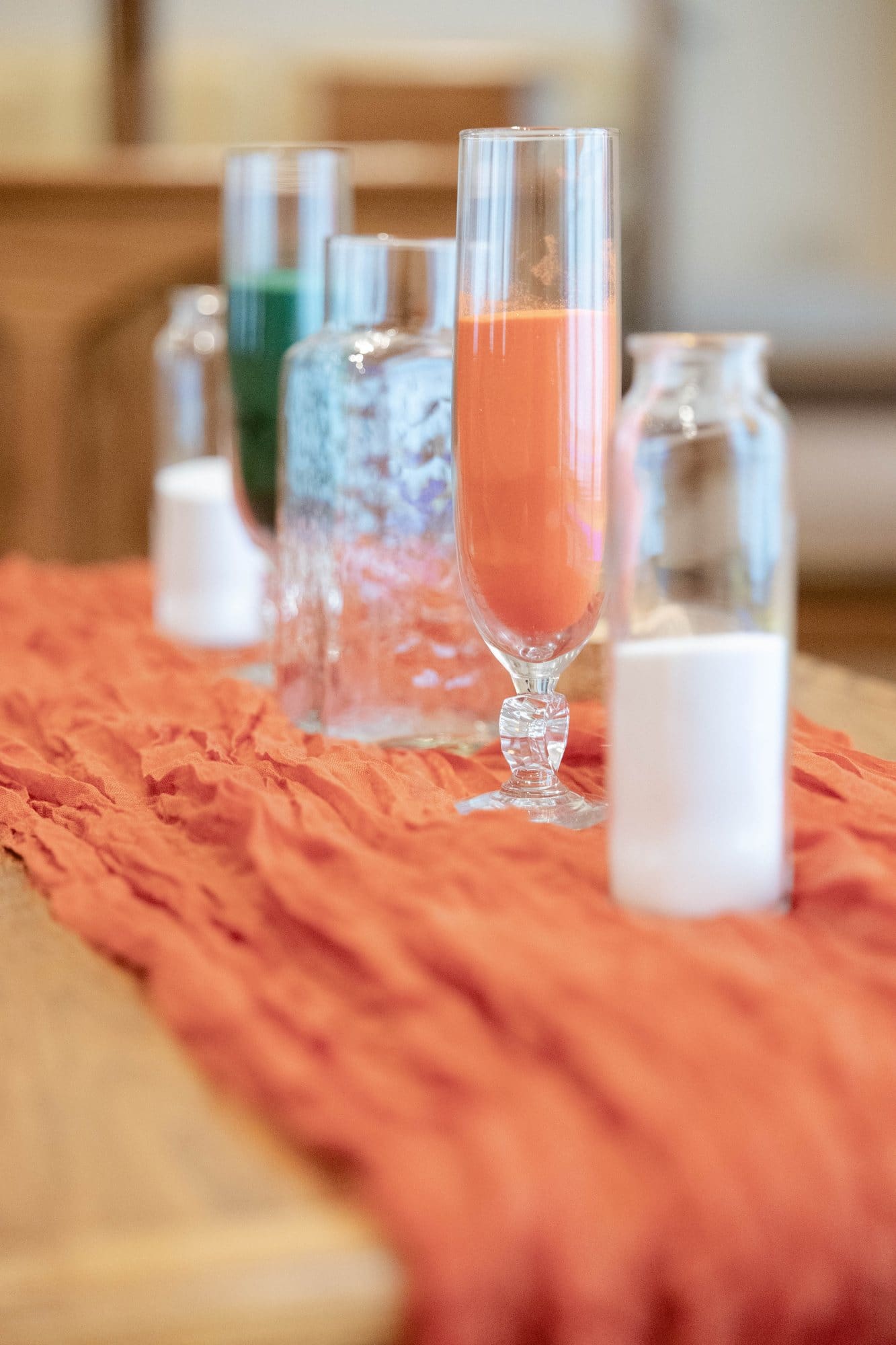 Glass vessels of emerald and copper sand set out for the unity ceremony on a copper gauze runner